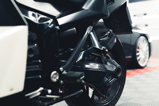 Low angle close-up shot of wheel of black motorcycle. Car salon. Garage interior. Horizontal indoor shot. High quality photo