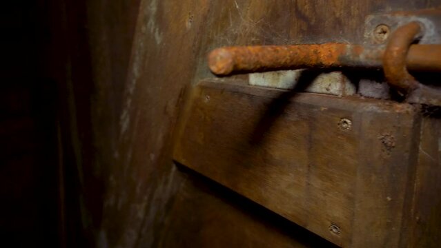rusty door latch of heavy wooden door with spider web