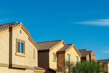 Row of modern houses in the neighborhood with visible gable style roofs and windows with front yard trees