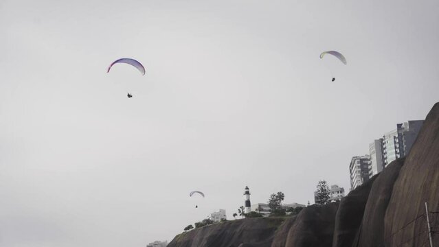 Paragliders Flying over Costa Verde, Lima, Peru. Daytime, Overcast. Slow motion.