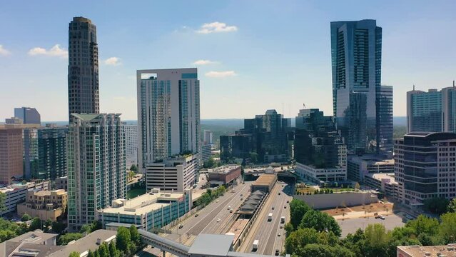 Slow moving drone shot of the highway passing through Buckhead in Atlanta, GA. Cars drive the highway near the MARTA subway station.