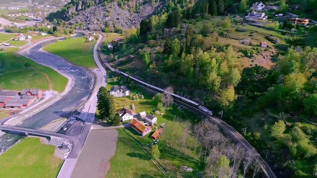 Beautiful aerial of a little village in beautiful Norwegian mountains and nature with a river flowing through on a Sunne day in Fl&aring;m