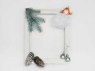 Home Christmas decoration made of white wooden frame, fir branch and cones, balls and a little Christmas fairy. Christmas background
