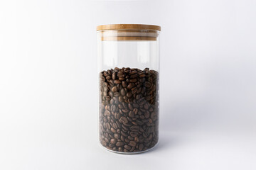 Glass jar with coffee beans inside. Front view