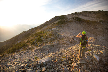 Backpacker blocks the sun with his hand while hiking in the evening.