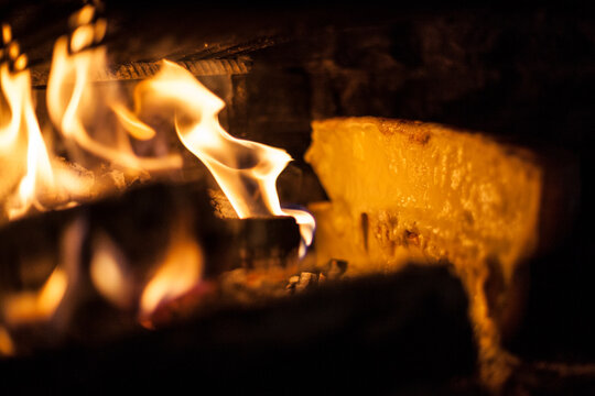 Raclette cheese is melted by a wood fire at a backcountry inn inside the Parc Naturel R&Atilde;&copy;gional du Vercors, France.