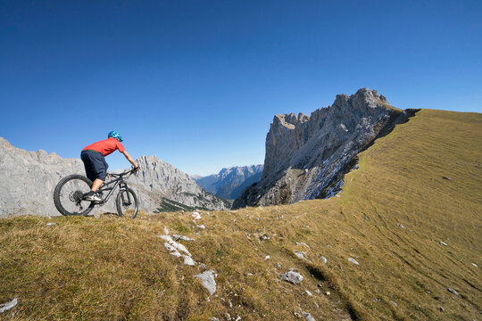 Mountain biker riding down hill in alpine landscape, Tyrol, Austria