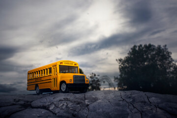 Yellow school bus toy model on country road.Back to school concept background.