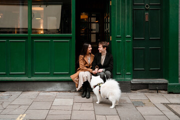 Couple with a dog sitting at the entrance of a pub