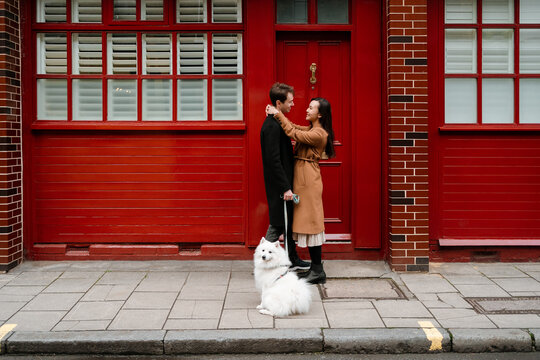 Lovers with their dog flirting out of a red house