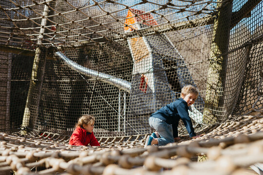Brother and sister playing on a climbing frame  in a park