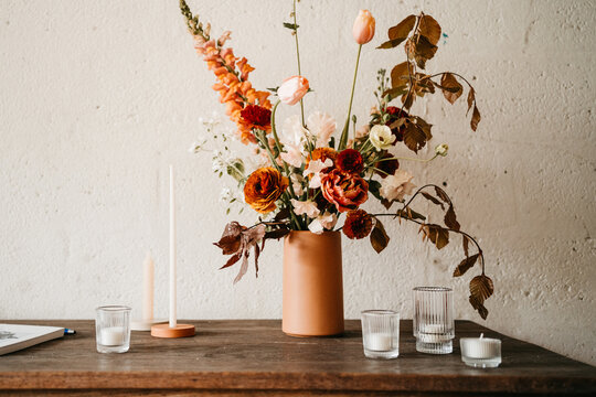 Orange flowers and candles on a rustic table indoors