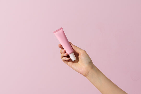 Woman Hand Hold A Blank Cosmetic Container Isolated On Pink.