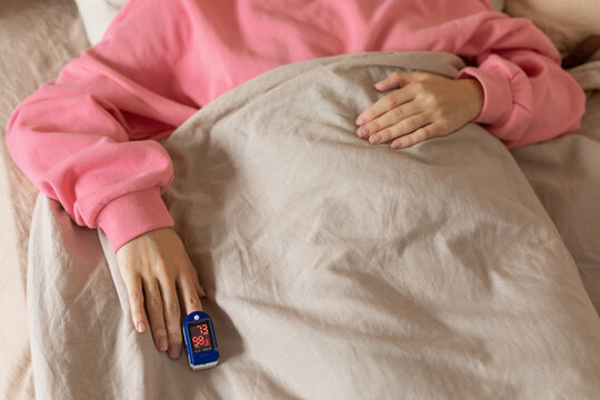 Pulse Oximeter On Woman's Finger In Bed