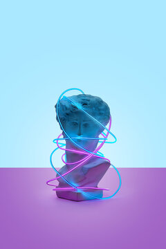 Antique statue wrapped in bright neon strip.