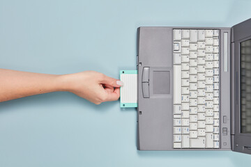 90s laptop with hand put floppy disk inside.