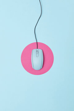 Vintage wired computer mouse on round pink pad.