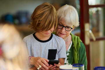 Grandmother and grandson use mobile.
