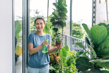 Housewife holding spray with water and humidifying her plants