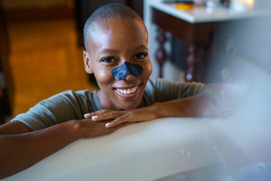 Portrait of happy female with blackhead cleansing strip on nose