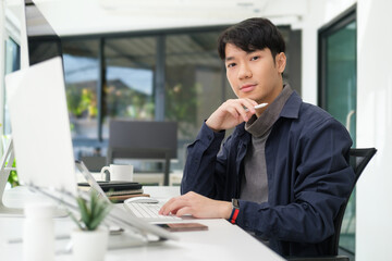 Portrait of young start up businessman sitting front of computer in his office and looking at camera.