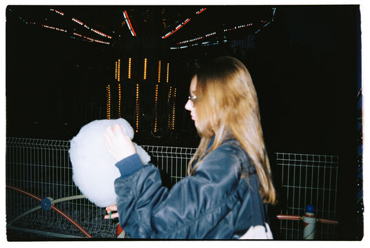 Girl eating candy cotton in amusement park
