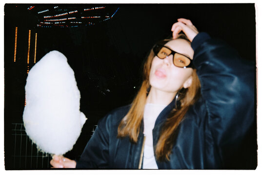 Girl eating candy cotton in amusement park
