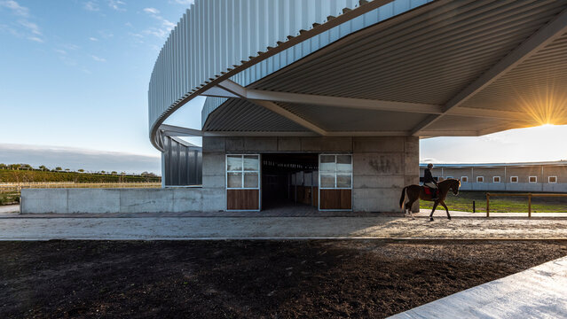Young rider leaving the stables with his horse at sunset