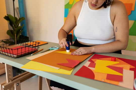 Female making crafts with color papers in studio