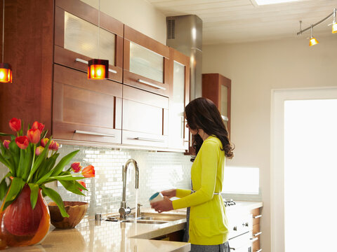 Woman Washing The Dishes In Kitchen