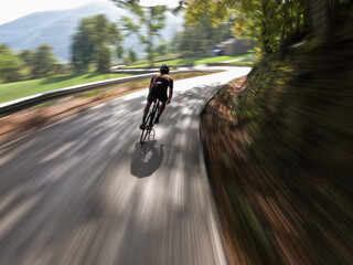 following a cyclist pedalling on a mountain road