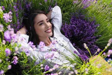 Young woman lying in lavender field on summer day