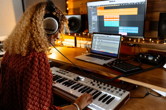 Back of Music producer at home studio using keyboard controller