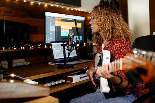 happy Music producer working at home studio recording guitar and voice