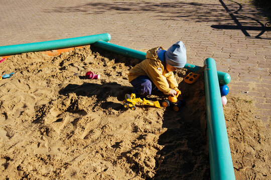 A little boy is playing in the sandbox.