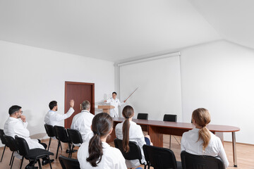 Doctor giving lecture in conference room with projection screen
