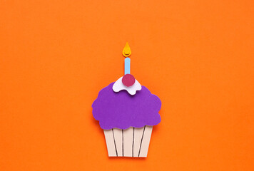 Birthday party. Paper cupcake on orange background, top view
