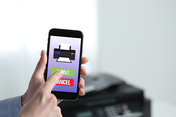 Man using printer management application on mobile phone indoors, closeup and space for text