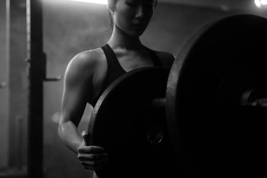 Young Asian female training in gym with weights at night