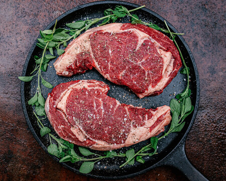 Raw Seasoned Steaks on Cast Iron Skillet