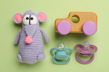 Flat lay composition with pacifiers and other baby stuff on pale green background
