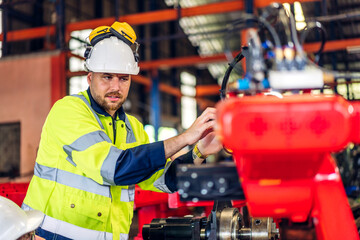 Professional machanic engineer technician industrial man wearing safety uniform working control with robot heavy machine in manufacturing  factory production line.business technology robot