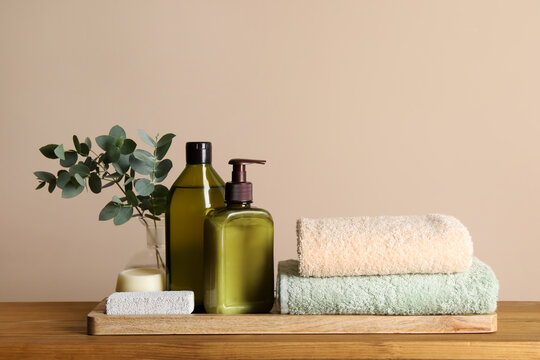 Solid Shampoo Bar And Bottles Of Cosmetic Product On Wooden Table Near Beige Wall