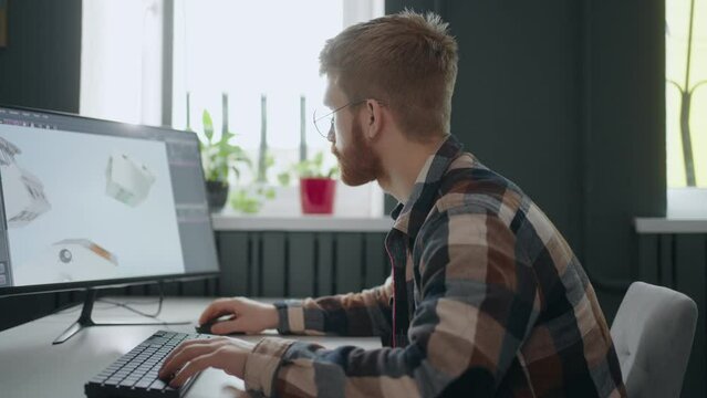 male creative designer using CAD system for projecting details of engine, creating 3D model