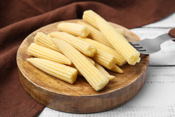 Pickled baby corn and fork on white wooden table, closeup