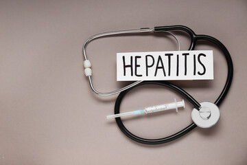 Word Hepatitis, stethoscope and syringe on beige background, flat lay. Space for text