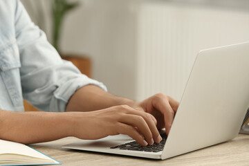 African American man typing on laptop at wooden table indoors, closeup
