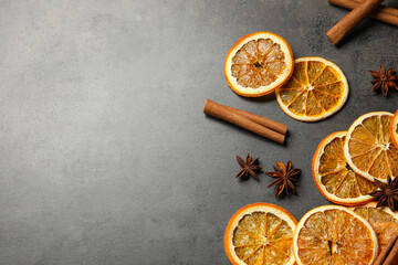 Dry orange slices, cinnamon sticks and anise stars on black table, space for text