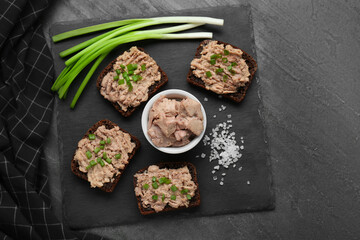 Obraz na płótnie Canvas Tasty sandwiches with cod liver, salt and green onion on grey table, top view