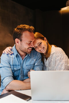 Happy couple using laptop in dark room